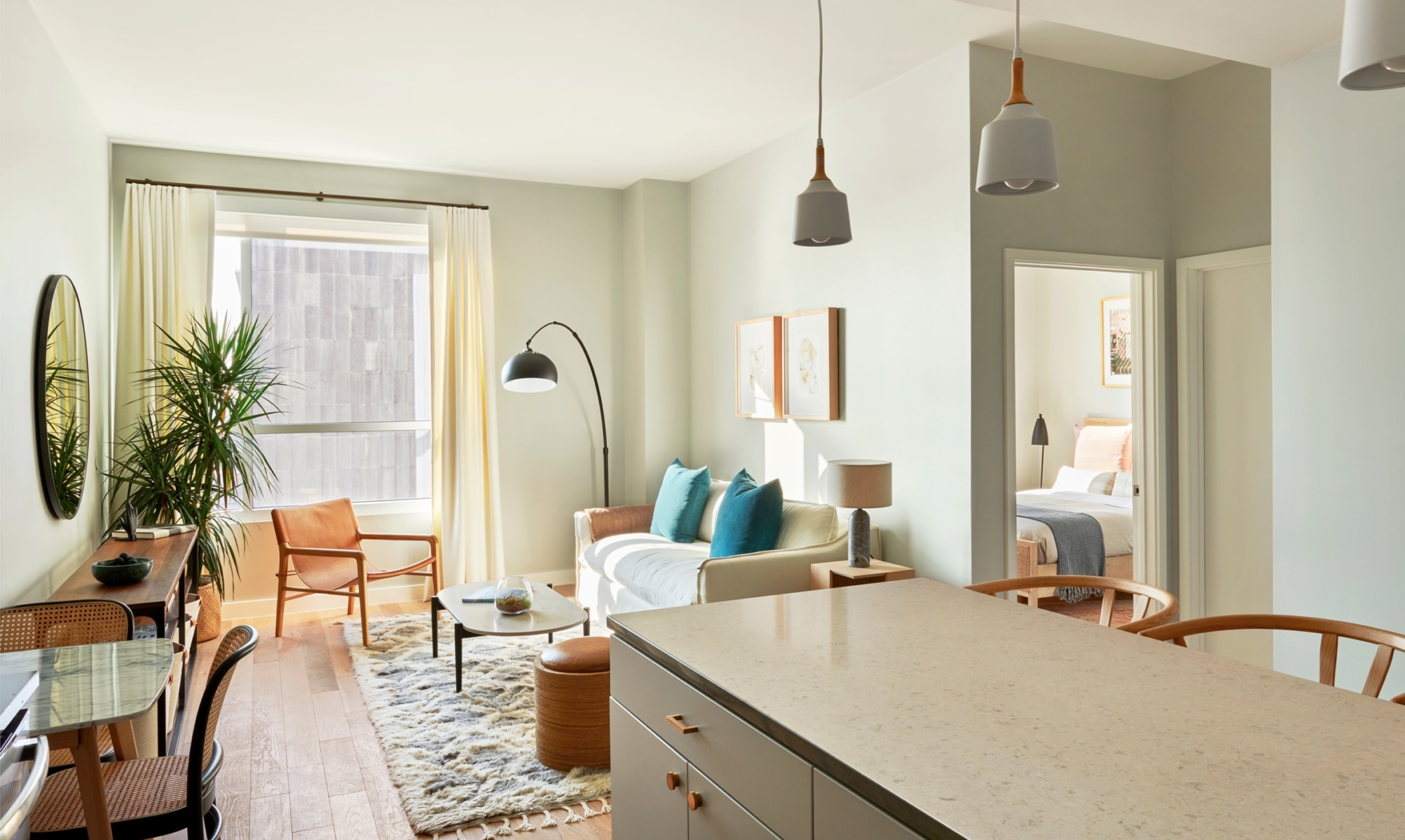 View from the kitchen of a spacious one bedroom apartment featuring floor-to-ceiling windows and modern furniture.