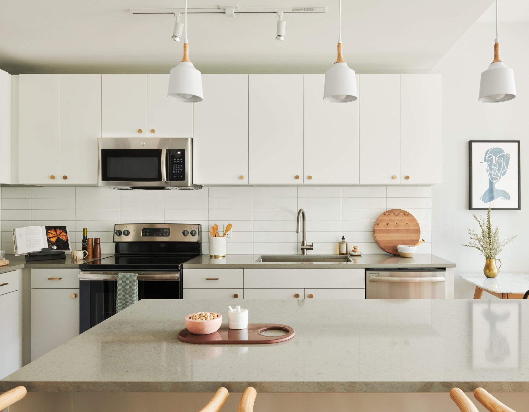 A kitchen with euro-style, white caninets and pendant lighting.